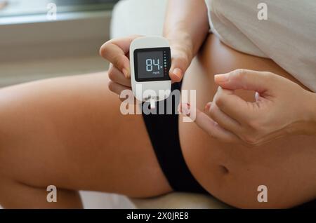 Donna incinta che usa un glucometro per misurare lo zucchero nel sangue. Abitudini sane e stile di vita durante la gravidanza. Foto Stock