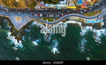 Video veduta aerea della tortuosa Malecon di Mazatlan, dove le auto viaggiano in contrasto con la bellezza delle onde che si infrangono contro la costa rocciosa della città. Foto Stock