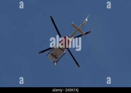 Elicottero di sorveglianza che vola sopra il cielo durante una giornata limpida e soleggiata Foto Stock