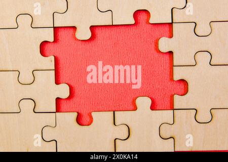 Una vista ravvicinata di pezzi di puzzle in legno incompleti sparsi su un vivace sfondo rosso Foto Stock