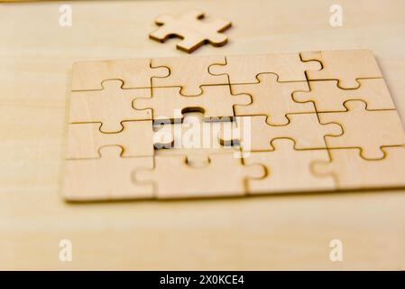 Una foto ravvicinata di pezzi di puzzle di legno infiniti sparsi su un tavolo di legno liscio Foto Stock