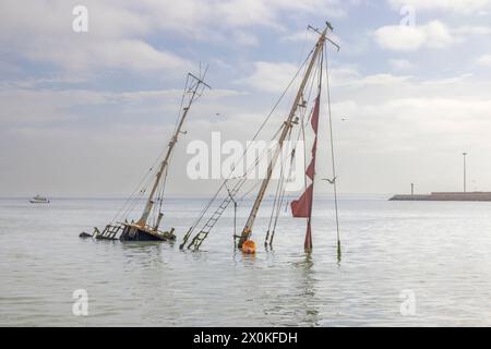 Foto di uno yacht a vela affondato con alberi che sporgono dall'acqua vicino a Walvis Bay in Namibia durante il giorno Foto Stock