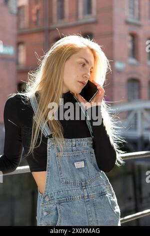 Una giovane donna al telefono nel quartiere dei magazzini di Speicherstadt ad Amburgo. Foto Stock