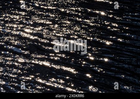 Riflessi di luce causati dalla luce solare sulla superficie di un lago, piccole onde e stelle, Germania Foto Stock