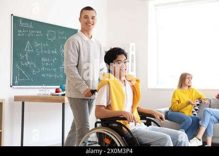 Adolescente con il suo compagno di classe in sedia a rotelle a scuola Foto Stock