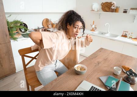 Affrettati donna d'affari afroamericana a fare colazione e a mettere il blazer in cucina Foto Stock