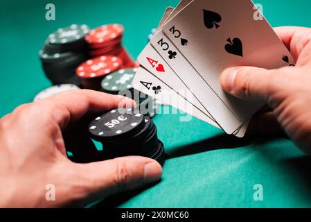 Giocare a poker nel casinò. Carte con due paia in mano al giocatore che fa una scommessa con fiches su uno sfondo verde del tavolo Foto Stock