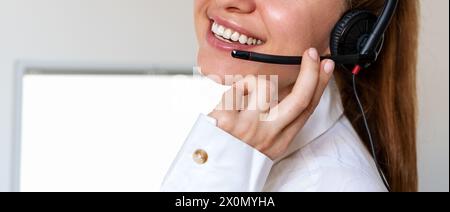 Concetto di help desk o helpline. Dipendente felice in ufficio. Agente del servizio clienti donna in cuffia. Foto Stock