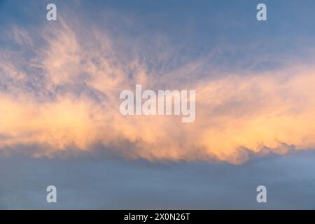 Un tramonto mozzafiato dipinge il cielo con una miscela di calde tonalità oro e blu, creando uno sfondo sereno perfetto per valorizzare il fascino visivo Foto Stock