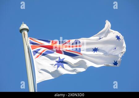 Bandiera australiana White Ensign che sventola in cima all'albero commemorativo HMAS Sydney 1 presso il forte Bradleys Head sulla riva nord di Sydney, NSW, Australia Foto Stock