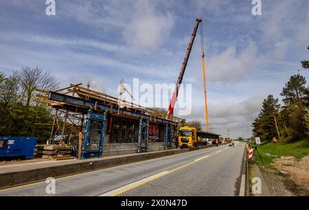 Owschlag, Germania. 13 aprile 2024. In un cantiere sull'autostrada A7 tra gli svincoli Owschlag e Rendsburg/Büdelsdorf, i componenti prefabbricati dei ponti vengono sollevati in posizione. La corsia in direzione di Amburgo sarà chiusa dal 12 aprile 2024 dalle 20:00 al 15 aprile 2024 alle 5:00. Le travi saranno consegnate prima al cantiere su caricatori bassi e poi sollevate in posizione utilizzando una gru da 500 tonnellate. Credito: Axel Heimken/dpa/Alamy Live News Foto Stock