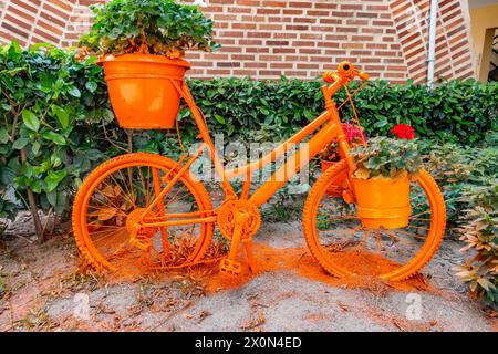 Una vecchia bicicletta, riutilizzata con vernice spray per trasformarla in una piantatrice da giardino decorativa e colorata Foto Stock