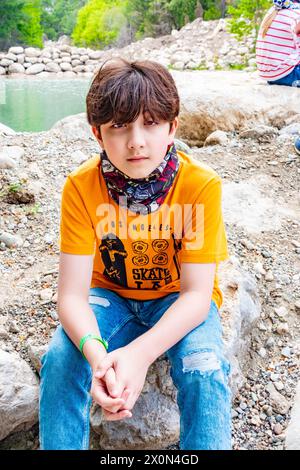 Ritratto di un ragazzo di 11 anni seduto su una roccia nel Goynuk Canyon vicino ad Antalya in Turchia Foto Stock