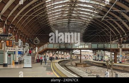 Una piattaforma della stazione ferroviaria, fiancheggiata da colonne, curva in lontananza. Una storica tettoia del XIX secolo è sopraelevata e una passerella pedonale collega il piano Foto Stock