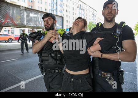 13 aprile 2024, Berlino, Germania: Continuando i loro sforzi per attirare l'attenzione su questioni climatiche urgenti, l'ultima generazione, la Letzte Generation, membri del gruppo di attivisti bloccò Frankfurter Allee, una delle rotte di traffico più antiche e cruciali di Berlino, il 13 aprile 2024. L'ultima generazione, un importante gruppo di attivismo climatico in Germania, è diventato sempre più visibile a causa delle loro proteste di alto profilo e dirompenti rivolte alle principali arterie stradali e agli spazi pubblici. Originatosi come parte di un'ondata globale di attivismo ambientale, il gruppo chiede che il governo tedesco si impegni a più aggressività Foto Stock