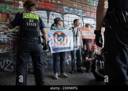 13 aprile 2024, Berlino, Germania: Continuando i loro sforzi per attirare l'attenzione su questioni climatiche urgenti, l'ultima generazione, la Letzte Generation, membri del gruppo di attivisti bloccò Frankfurter Allee, una delle rotte di traffico più antiche e cruciali di Berlino, il 13 aprile 2024. L'ultima generazione, un importante gruppo di attivismo climatico in Germania, è diventato sempre più visibile a causa delle loro proteste di alto profilo e dirompenti rivolte alle principali arterie stradali e agli spazi pubblici. Originatosi come parte di un'ondata globale di attivismo ambientale, il gruppo chiede che il governo tedesco si impegni a più aggressività Foto Stock