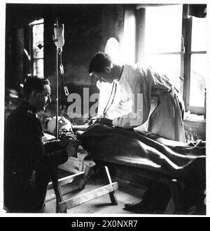 Un paziente riceve una trasfusione di plasma sul campo, con il flacone di plasma sospeso e collegato al braccio tramite un ago cavo, come documentato dall'esercito britannico. Foto Stock