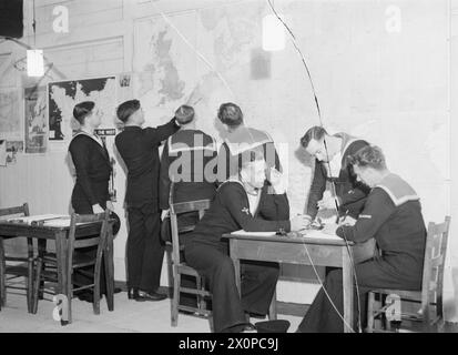 AL "SAILOR'S REST" DI HARWICH. 27 LUGLIO 1944, HARWICH. È STATA APERTA UNA VECCHIA STALLA CONVERTITA DA RATING IN UNA SALA DI RIPOSO E INFORMAZIONE. - Un maestro di scuola navale che guarda la mappa dell'Europa con gli uomini in bagno Foto Stock