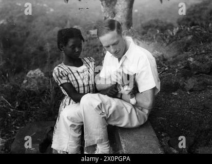 SOTTUFFICIALE PALENTHORPE A LEICESTER, UN PICCOLO VILLAGGIO VICINO FREETOWN, SIERRA LEONE. - Il sottufficiale Palenthorpe, conosciuto come 'Mister Ginger', con una bambina e il suo gatto ferito.titolo originale della seconda guerra mondiale e didascalia rilasciata con questa fotografia:MARINAIO CHE È DIVENTATO SCUDIERO DEL VILLAGGIO AFRICANO. GINGER-HAIRED PETTY OFFICER PALENTHORPE È LO "SCUDIERO" DI LEICESTER, IL PICCOLO VILLAGGIO AFRICANO VICINO FREETOWN, SIERRA LEONE. DOPO 18 MESI DI CONSIGLI AMICHEVOLI AI NATIVI, ESISTE ORA UNA COMPLETA FIDUCIA RECIPROCA E COMPRENSIONE TRA LORO E 'MISTER GINGER?. È IL PRESIDENTE DEL CONSIGLIO PARROCCHIALE, Foto Stock