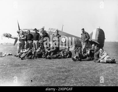 OPERAZIONI DELLA ROYAL AIR FORCE SU ALBANIA E GRECIA, 1940-1941. - Piloti del No. 33 Squadron RAF, a Larissa, Grecia, con Hawker Hurricane Mark i, V7419, in background. In piedi (da sinistra a destra); ufficiali pilota W Winsland, R Dunscombe (nato il 22 maggio 41), C A C Chetham (nato il 15 aprile 41) e P R W Wickham, Flying Officers D T Moir e H J Starrett (morto per ustioni il 22 aprile 41): Seduta (da sinistra a destra); Flying Officer e J 'Timber' Woods (k.i.a. 17 giugno 41), Flying Officer F Holman (k.i.a. 20 maggio 41), Flight Lieutenant A M Young, Flying Officer V C 'Woody' Woodward, Squadron leader M St J 'Pat' Pat Foto Stock