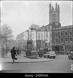 SERVIZIO DI TRASFUSIONI DI SANGUE DELL'ESERCITO DI BRISTOL, FEBBRAIO 1944 - Una trafficata scena di Colston Avenue a Bristol, che mostra pedoni e veicoli che svolgono le loro attività quotidiane. La statua di Edmund Burke è stata ricoperta da tavole che pubblicizzano la campagna di donazione del sangue del Ministero dell'informazione. Oltre a un'illustrazione di un militare ferito e le date della campagna, il poster riporta le parole: "Iscriviti come donatore di sangue per il secondo fronte". Sullo sfondo, i grandi magazzini di Thos. Reynolds and Sons Ltd, un mercante di costruttori e monger di ferro e e e Taylor and Sons Ltd, un cuoio Foto Stock