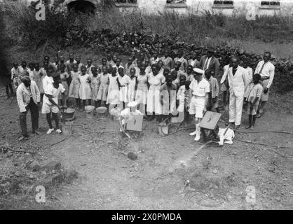 SOTTUFFICIALE PALENTHORPE A LEICESTER, UN PICCOLO VILLAGGIO VICINO FREETOWN, SIERRA LEONE. - L'organizzazione Village A R P, con gli scolari che assistono a una dimostrazione di combattimenti incendiari con bombe.titolo originale della seconda guerra mondiale e DIDASCALIA rilasciata con questa fotografia:SAILOR CHE È DIVENTATO IL VILLAGGIO AFRICANO SQUIRE. GINGER-HAIRED PETTY OFFICER PALENTHORPE È LO "SCUDIERO" DI LEICESTER, IL PICCOLO VILLAGGIO AFRICANO VICINO FREETOWN, SIERRA LEONE. DOPO 18 MESI DI CONSIGLI AMICHEVOLI AI NATIVI, ESISTE ORA UNA COMPLETA FIDUCIA RECIPROCA E COMPRENSIONE TRA LORO E 'MISTER GINGER?. È IL PRESIDENTE DELLA PAR Foto Stock