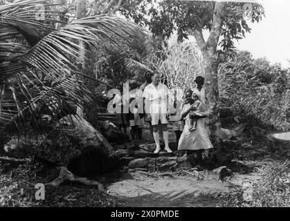 SOTTUFFICIALE PALENTHORPE A LEICESTER, UN PICCOLO VILLAGGIO VICINO FREETOWN, SIERRA LEONE. - Il sottufficiale Palenthorpe che cammina con una famiglia di Krio, o creoli della Sierra Leone, dal villaggio di LeicesterOriginal seconda guerra mondiale titolo e didascalia con questa fotografia: SAILOR CHE È DIVENTATO IL VILLAGGIO AFRICANO SQUIRE. GINGER-HAIRED PETTY OFFICER PALENTHORPE È LO "SCUDIERO" DI LEICESTER, IL PICCOLO VILLAGGIO AFRICANO VICINO FREETOWN, SIERRA LEONE. DOPO 18 MESI DI CONSIGLI AMICHEVOLI AI NATIVI, ESISTE ORA UNA COMPLETA FIDUCIA RECIPROCA E COMPRENSIONE TRA LORO E 'MISTER GINGER?. LUI È IL Foto Stock