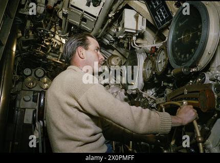 A BORDO DEL SOTTOMARINO HM TRIBUNE, 1942 - il secondo Coxswain della HMS TRIBUNE, il sottufficiale Hedley Charles Woodley alla sua stazione di immersione sugli idrovolanti. L'indicatore di profondità nell'immagine mostra che il sottomarino si trova sulla superficie. La fotografia è stata quindi posta durante le riprese del film 'Close Quarters' Royal Navy, HMS Tribune, Submarine, (1938) Foto Stock