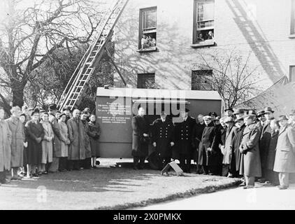 PRESENTAZIONE DI UN'AUTO DA CUCINA AL ROYAL NAVAL ARMAMENT DEPOT PRIDDY'S HARD, UN REGALO DI KINGSTON, ONTARIO. - Un'auto da cucina e' il dono dell'ordine della Stella Orientale, Distretto No. 13, Kingston, Ontario, al Royal Naval Armament Depot, Priddy's Hard a Gosport. Questa immagine, scattata sul prato di fronte all'Officer's Quarters mostra (da sinistra a destra) il colonnello Unwin Simson, il contrammiraglio Sir Arthur Bromley e l'ammiraglio Sir Chas poco in piedi davanti al rimorchio. Altri membri della forza lavoro sono presenti Foto Stock