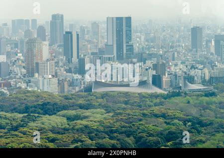 Un lussureggiante parco verde sorge in netto contrasto con gli alti edifici circostanti di una città densamente popolata. Un cielo nebuloso suggerisce sia la prima mattina che la mattina Foto Stock