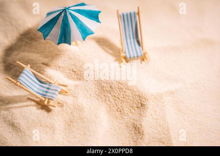 Lettini e ombrelloni a righe sulla sabbia gialla e pulita della spiaggia Foto Stock