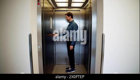 Vista posteriore di Un uomo che utilizza l'ascensore Foto Stock