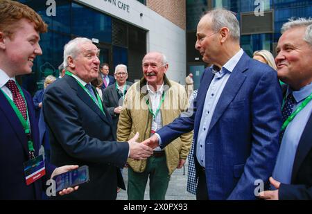 L'ex Taoiseach Bertie Ahern incontra e stringe la mano con l'attuale leader di Fianna Fail e Tanaiste Micheal Martin mentre arriva al Fianna Fail Ard Fheis, al Royal Convention Centre di Dublino. Data foto: Sabato 13 aprile 2024. Foto Stock