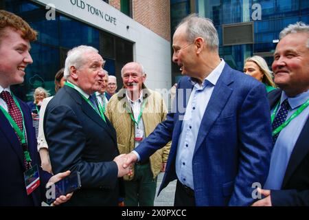 L'ex Taoiseach Bertie Ahern incontra e stringe la mano con l'attuale leader di Fianna Fail e Tanaiste Micheal Martin mentre arriva al Fianna Fail Ard Fheis, al Royal Convention Centre di Dublino. Data foto: Sabato 13 aprile 2024. Foto Stock