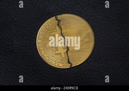 Halbierte Bitcoin Münze auf schwarzem Untergrund. Symboldfoto für das Bitcoin dimezzare *** ha dimezzato la moneta Bitcoin su sfondo nero. Foto simbolo per Foto Stock