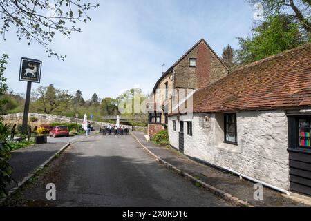 Il pub White Hart accanto allo Stopham Bridge con persone sedute fuori nel villaggio di Stopham, West Sussex, Inghilterra, Regno Unito Foto Stock