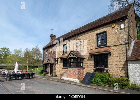 Pub White Hart con gente seduta fuori nel villaggio di Stopham, West Sussex, Inghilterra, Regno Unito Foto Stock