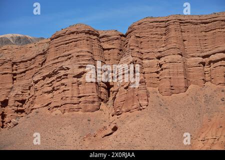 Destinazione di viaggio, famoso punto di riferimento del Kirghizistan. Colonne rocciose di arenaria rossa nel canyon di Konorchek, depositi eolici, scogliere a picco causate da erosioni del suolo Foto Stock