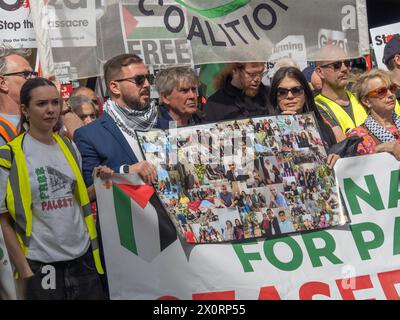 Londra, Regno Unito. 13 aprile 2024. Foto di alcune delle vittime trattenute sullo striscione. Migliaia di persone marciano attraverso Londra per una manifestazione in Piazza del Parlamento in una giornata di azione in tutto il paese per chiedere un cessate il fuoco immediato, che la Gran Bretagna smetta di vendere armi a Israele e chieda una Palestina libera. Israele sta usando armi britanniche, tecnologie di sorveglianza e attrezzature militari negli attacchi che hanno ucciso oltre 32.000 persone a Gaza dal 7 ottobre. Una piccola contro-protesta sionista gridò loro ad Aldwych. Peter Marshall/Alamy Live News Foto Stock