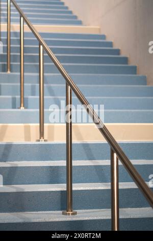 Scala blu chiaro con ringhiera in metallo grigio in un edificio Foto Stock