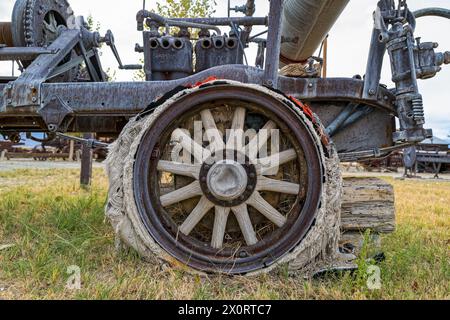 Uno pneumatico in rovina sta cadendo da una ruota con razze in legno e un cerchio in metallo su un antico verricello Foto Stock