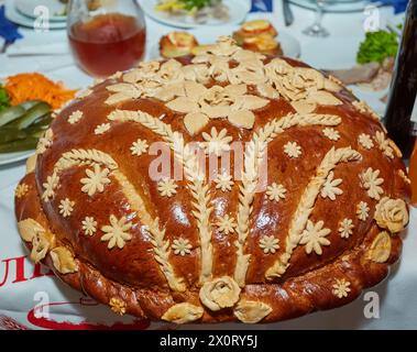 Pane fresco decorato ucraino con sale giace sul tavolo, accanto all'asciugamano ricamato. Tradizioni di nozze ucraine. Torta gustosa. Foto Stock