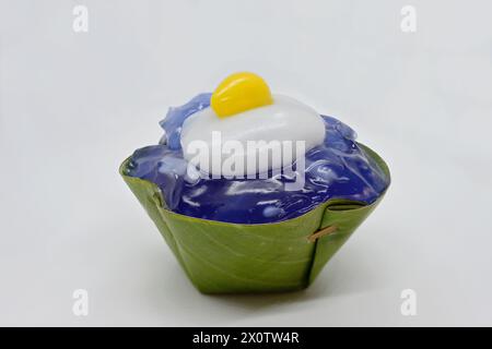 Primo piano di un dessert Khanom Tako "capovolto", con gelatina di piselli e ginkgo giallo condito con crema di cocco "Sunny-side up" in tazza di foglie di panda Foto Stock