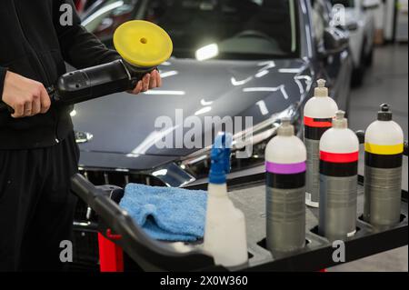 Il master applica una composizione speciale al dispositivo per la lucidatura della superficie della carrozzeria della vettura. Foto Stock