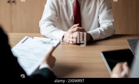 Donna responsabile delle risorse umane che legge il curriculum e scrive i dati su tablet durante il colloquio di lavoro con un candidato maschio. Foto Stock