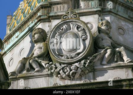 Primo piano di un cartiglio fiancheggiato da putti in cima alla Torre dell'Orologio nel centro di Brighton. Foto Stock