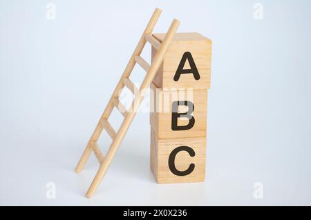 Testo ABC su cubi di legno con scala su sfondo bianco. Concetto di apprendimento. Foto Stock