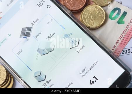 App per pannelli solari su uno smartphone che monitora l'elettricità generata dal Sole con bolletta di denaro e elettricità Foto Stock