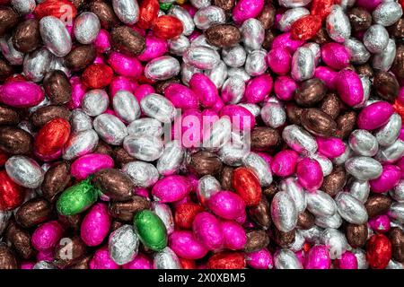 Molte caramelle per il passato. Uova di pasqua colorate al cioccolato. Mucchio o gruppo di uova di pasqua ricoperte di foglie di cioccolato multicolore Foto Stock