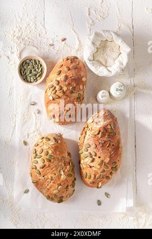 Panini sani e fatti in casa con semi di zucca e ingredienti in tavola. Panini cotti in una panetteria. Foto Stock